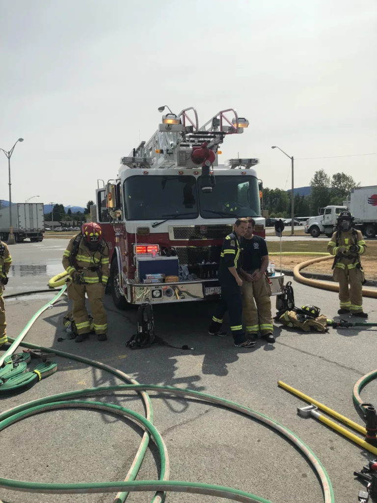 Kitimat firefighters standing in front of the ladder truck during hose training